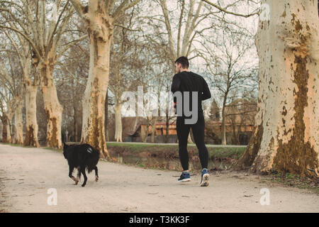 Jeune athlète exécutant canicross avec son border collie dog .jeune homme s'exécute avec son chien city park. Concept de vie sain.chien actif vie conc Banque D'Images