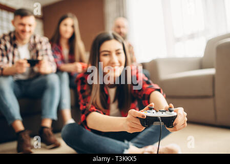 Amis avec une manette de console à la maison joue plat Banque D'Images