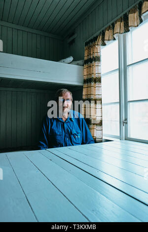 Un portrait d'un homme scandinave et propriétaire d'une pêche du hareng norvégien 1950 Gare assis dans l'un de l'original 6 dortoirs de l'équipage à quai. Banque D'Images
