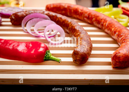 Déco a des saucisses, poivrons et oignons rouges placés sur planche en bois. Banque D'Images