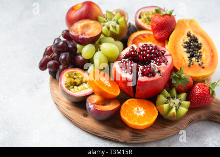 Plateau de fruits délicieux fruits de la passion oranges papaye grenade sur planche de bois sur blanc, selective focus Banque D'Images