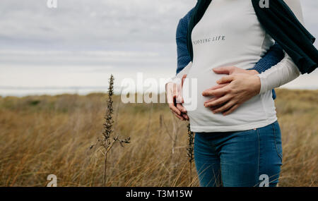 Enceinte avec partner hugging and holding belly Banque D'Images