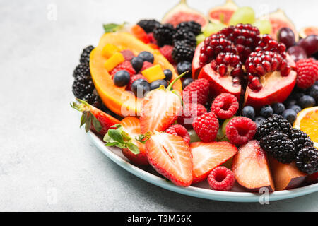 Plateau de fruits délicieux raisins oranges papaye grenade baies sur la plaque sur le blanc, selective focus Banque D'Images