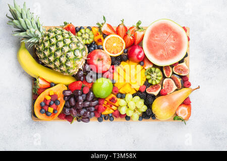 Arc-en-ciel cru sain de fruits oranges fraises Papaye Mangue ananas myrtilles pastèque obn planche en bois sur béton léger arrière-plan, Vue de dessus, selective focus Banque D'Images