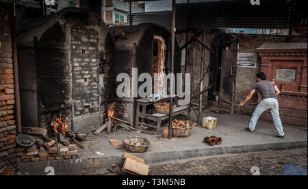 Les hommes de poterie cuisson dans un four Bhaktapur, Népal Banque D'Images