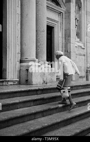 Femme monte les marches de la cathédrale, entrée Poljana Marina Držića, Dubrovnik, Croatie. Version noir et blanc Banque D'Images