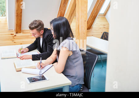 Deux étudiants concentrés tout en apprenant dans un séminaire ou un examen collégial Banque D'Images