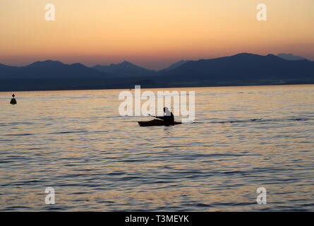 Rameur solitaire sur le lac au coucher du soleil Banque D'Images