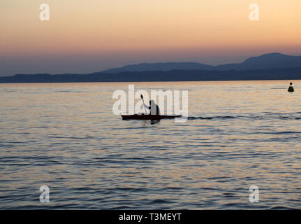 Rameur solitaire sur le lac au coucher du soleil Banque D'Images