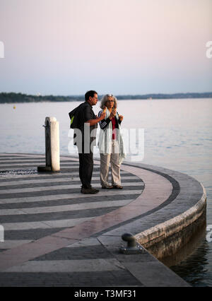 LAZISE, ITALIE - 5 mai 2016 couple âgé : sur une promenade à la recherche au coucher du soleil au lac de Garde à Torri del Benaco, Italie Banque D'Images