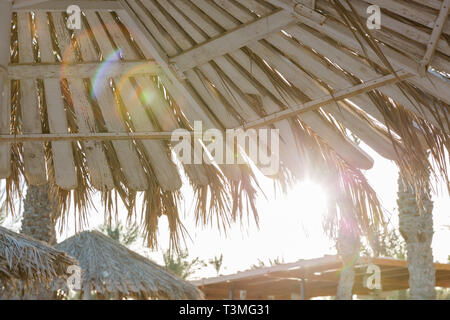 Coucher du soleil d'été des parasols sur la plage de sable. Tons vintage. Banque D'Images