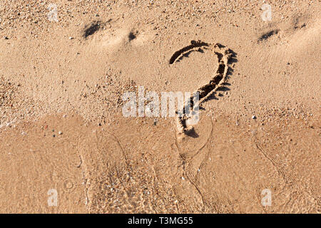 Signe d'interrogation sur la plage de sable près de la mer. Concept de dilemme, réponse et question. Banque D'Images