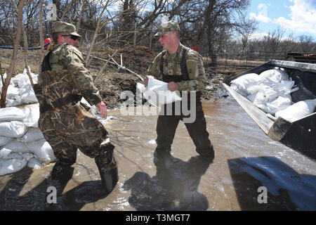 La Garde nationale armée du Dakota du Nord, prendre la parole à l'eau d'inondation comme ils place de sable pour bloquer l'augmentation des crues à partir de la sauvegarde par une buse en une ferme en milieu rural comté de Cass 8 Avril 2019 près de West Grand Forks, Dakota du Nord. Les inondations records devrait s'aggraver comme une tempête à la fin de l'hiver de barils dans le midwest des États-Unis au cours des prochains jours. Banque D'Images