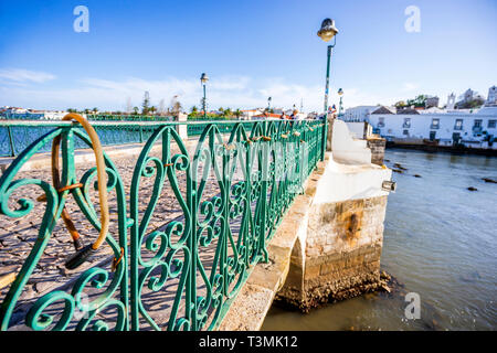 Pont romain avec clôture en acier vert sur In The Golfer's Paradise River à Tavira, Algarve, Portugal Banque D'Images