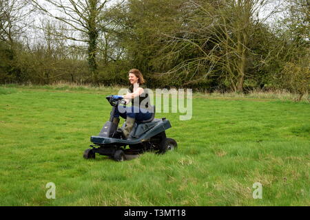 Femme de couper le gazon sur un sit sur tondeuse, Suffolk, Angleterre Banque D'Images