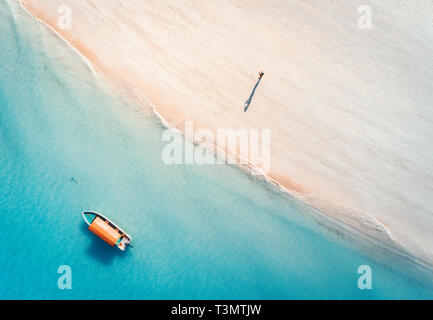 Vue aérienne du bateau de pêche en eau bleu clair et l'homme sur la plage de sable au coucher du soleil en été. Vue de dessus du bateau. De l'océan Indien. Billet à Zanzibar Banque D'Images