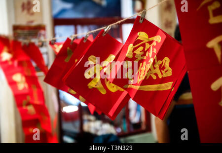 Or chinois bon mot dans le papier rouge pendaison avec corde en bas et l'éclairage de nuit ombre sombre. Banque D'Images