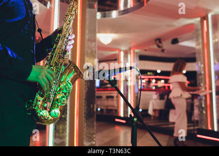 Saxophone d'or dans les mains d'un musicien près du microphone Banque D'Images
