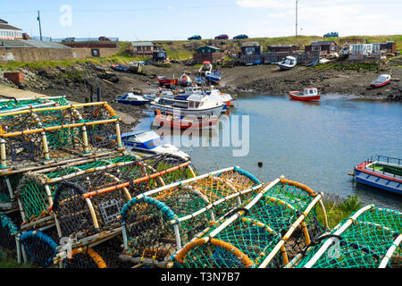 Bateaux de pêche échoués à marée basse dans le port de trou Rhône-Alpes, un jour de printemps avec des casiers à crabe ou homard traditionnel au premier plan à Teesmouth Redcar Banque D'Images