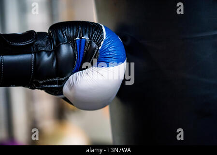 Concept de boxe. Main de boxer dans les sacs de sable noir gant hits c Banque D'Images