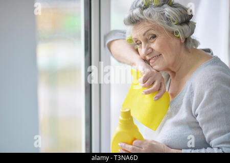 Belle Senior woman posing et fenêtre de nettoyage à la maison Banque D'Images