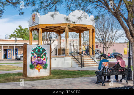 Les cadres supérieurs l'homme et la femme s'asseoir sur un banc de parc près de la tonnelle dans Old Mesilla Plaza, Mesilla, New Mexico, USA. Banque D'Images