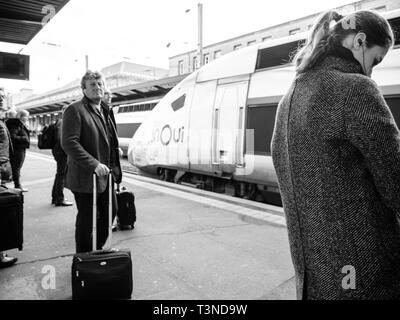 Paris, France - Mar 19, 2019 : Les banlieusards attendent impatiemment près de fast train TGV InOui dans le centre de la Gare de l'Est gare parisienne - matin ensoleillé sur la plate-forme ferroviaire - noir et blanc Banque D'Images