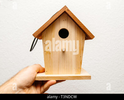 Image main d'hommes adultes nicheurs oiseaux holding birdhouse maison prête à être installée dans le jardin sur un arbre Banque D'Images