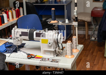 Machine à coudre industrielle blanc électrique dans un atelier de couture et de travail avec des tissus. Banque D'Images