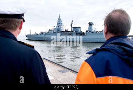 Wilhelmshaven, Allemagne. Apr 11, 2019. Un soldat de la marine et un employé de la base navale d'observer le départ de la frégate 'Hessen'. Pendant six mois, 'Hessen' va coopérer avec le garde-côtes grecs et turcs et l'Agence européenne pour la garde côtière et garde-frontière dans la mer Egée. Credit : Hauke-Christian Dittrich/dpa/Alamy Live News Banque D'Images