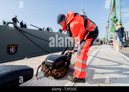 Wilhelmshaven, Allemagne. Apr 11, 2019. Un employé de la base navale se détache une corde d'un bollard avant de la frégate 'Hessen' s'en va. Pendant six mois, 'Hessen' va coopérer avec le garde-côtes grecs et turcs et l'Agence européenne pour la garde côtière et garde-frontière dans la mer Egée. Credit : Hauke-Christian Dittrich/dpa/Alamy Live News Banque D'Images