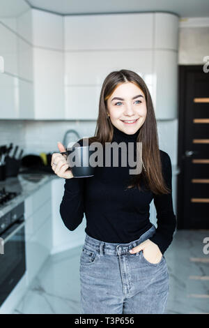 Partager vos sentiments. Cheerful nice woman smiling et boire le thé dans la cuisine Banque D'Images