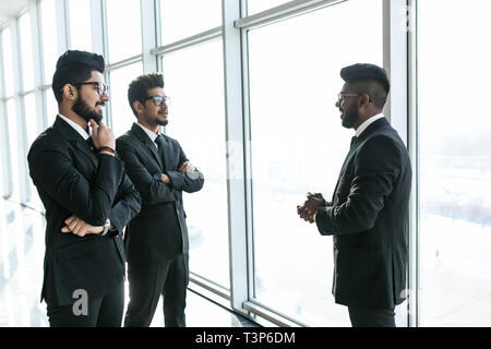 Silhouettes de trois dirigeants de sociétés asiatiques tenir devant les fenêtres discuter affaires . Banque D'Images