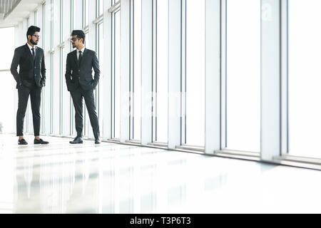 Deux affaires indiens confiant shaking hands and smiling in office Banque D'Images