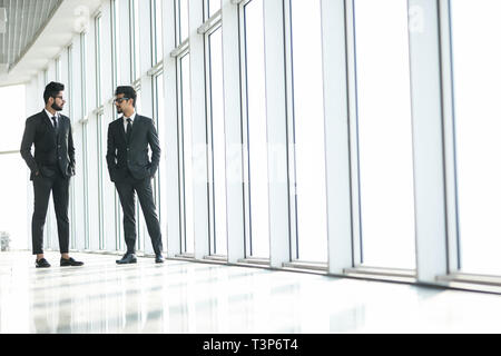 Deux affaires indiens confiant shaking hands and smiling in office Banque D'Images