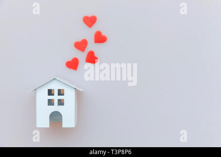 Tout simplement minimaliste avec blanc miniature toy house et coeur rouge isolé sur fond blanc. L'assurance des biens hypothécaires dream home concept. Télévision Banque D'Images