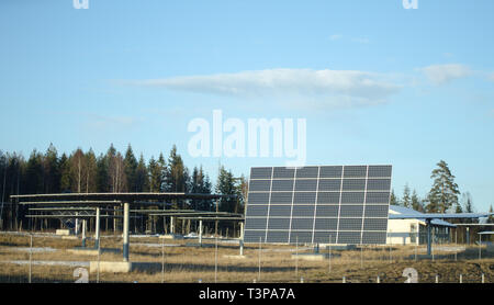 Des panneaux solaires dans le groupe sur un champ avec un ciel bleu au début du printemps avec de la neige laissée sur l'herbe. Banque D'Images