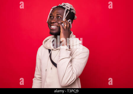 Young African American man making a phone call sur son smartphone sur fond rouge Banque D'Images