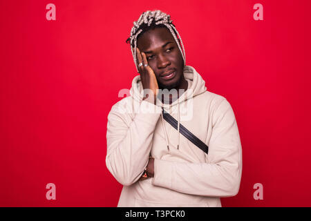 Closeup portrait of triste peine jeune homme menton sur le poing, pensant rêver profondément au sujet de quelque chose vous regarde la caméra, isolé sur fond rouge Banque D'Images