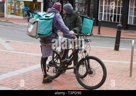 Deux Deliveroo location riders livraison dans le centre-ville de Reading Banque D'Images