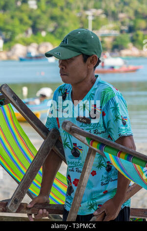 Un homme d'embauche vente de chaises longues sur la plage de Patong, Phuket, Thailand Banque D'Images