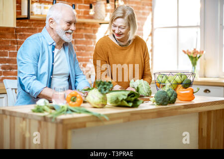 Cheerful senior couple salade avec des ingrédients frais et sain sur la cuisine à la maison. Concept de la saine alimentation chez les personnes âgées Banque D'Images