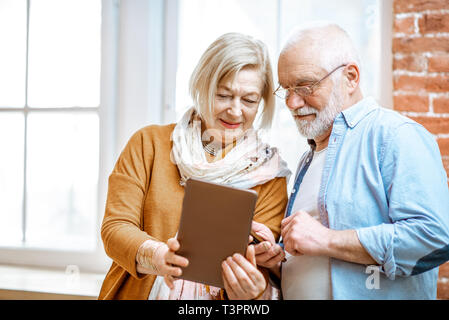 Belle senior couple Standing together près de la fenêtre à la maison Banque D'Images