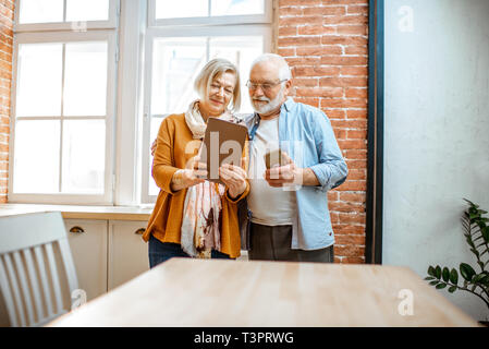 Belle senior couple Standing together près de la fenêtre à la maison Banque D'Images