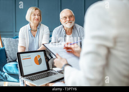 Happy senior couple lors de la réunion avec l'agent ou conseiller financier, la signature d'un accord dans le bureau confortable Banque D'Images
