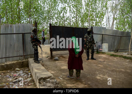 Paramilitaires indiennes vu hommes montent la garde comme un électeur du Cachemire vu quitter le bureau de scrutin dans Shadipora. Le vote a commencé pour deux sièges parlementaires dans le Cachemire indien au milieu d'une sécurité rigoureuse et un appel au boycott par les séparatistes. Des policiers armés et des soldats paramilitaires en tenue de scrutin surveillé les engrenages et les routes à proximité. Banque D'Images