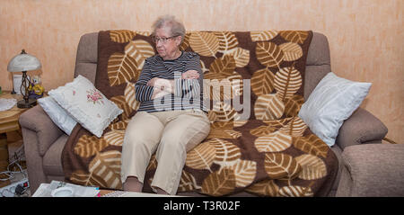 Plus de 80 ans grand-mère assise sur un sofa Banque D'Images