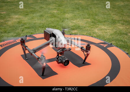 Un DJI Inspirer 2 drone professionnel sur le sol sur un tapis protecteur orange avec de l'herbe entourant Banque D'Images