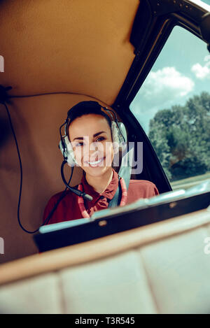 Belle femme avec les cheveux attachés et large sourire portant des écouteurs Banque D'Images