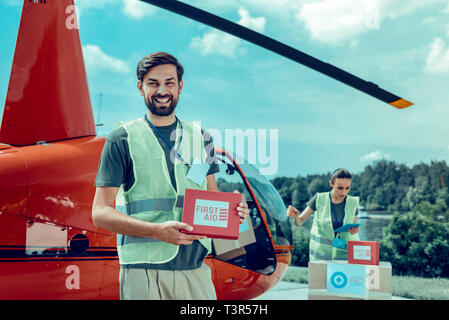 Brun court excité comme travail et bénévolat holding trousse de premiers secours Banque D'Images